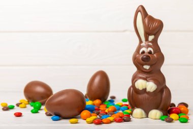 Açık dokuma masasında paskalya çikolatası tavşanı. Çikolatalı yumurta ve diğer tatlılar. Paskalya kutlaması. Paskalya tatlıları masada. Mesaj için yer. Boşluğu kopyala.