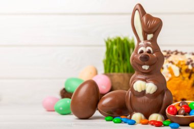 Açık dokuma masasında paskalya çikolatası tavşanı. Çikolatalı yumurta ve diğer tatlılar. Paskalya kutlaması. Paskalya tatlıları masada. Mesaj için yer. Boşluğu kopyala.