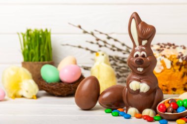 Açık dokuma masasında paskalya çikolatası tavşanı. Çikolatalı yumurta ve diğer tatlılar. Paskalya kutlaması. Paskalya tatlıları masada. Mesaj için yer. Boşluğu kopyala.