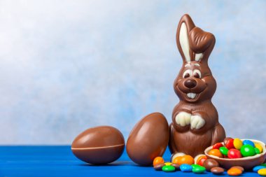 Açık dokuma masasında paskalya çikolatası tavşanı. Çikolatalı yumurta ve diğer tatlılar. Paskalya kutlaması. Paskalya tatlıları masada. Mesaj için yer. Boşluğu kopyala.