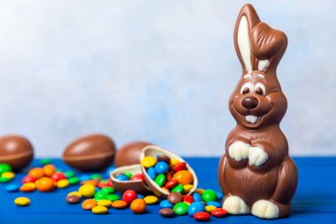 Açık dokuma masasında paskalya çikolatası tavşanı. Çikolatalı yumurta ve diğer tatlılar. Paskalya kutlaması. Paskalya tatlıları masada. Mesaj için yer. Boşluğu kopyala.