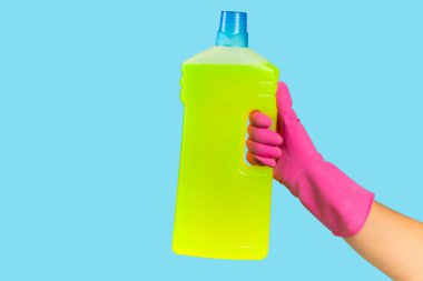 Plastik koruyucu eldivenli bir temizlikçinin elinde mavi arka planda bir şişe temizlik kimyasalı bulunur. Ticari temizlik şirketi. Bahar temizliği. Metin veya logo için boşluk.