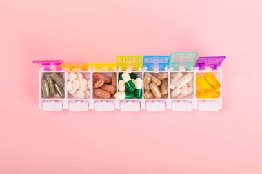 Vitaminler ve takviyeler. Pembe arka planda, ilaç kutusundaki vitamin haplarının çeşitliliği. Her gün için multivitamin. Besleyici takviyeler. Düz yatıyordu. Metin için boşluk. Boşluğu kopyala