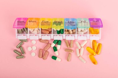 Vitaminler ve takviyeler. Pembe arka planda, ilaç kutusundaki vitamin haplarının çeşitliliği. Her gün için multivitamin. Besleyici takviyeler. Düz yatıyordu. Metin için boşluk. Boşluğu kopyala