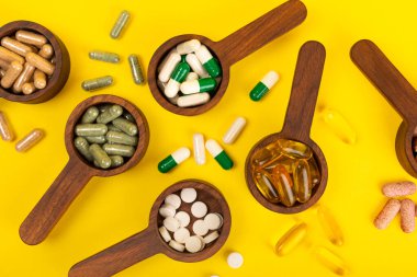 Vitaminler ve takviyeler. Ahşap bir kaşıkta çeşitli vitamin hapları. Taze ve sağlıklı meyveli Multivitaminler. Yiyecek takviyeleri. Düz yatıyordu. Metin için boşluk. Boşluğu kopyala