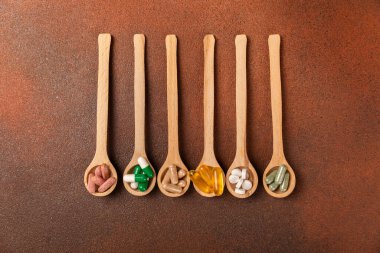 Vitaminler ve takviyeler. Ahşap bir kaşıkta çeşitli vitamin hapları. Taze ve sağlıklı meyveli Multivitaminler. Yiyecek takviyeleri. Düz yatıyordu. Metin için boşluk. Boşluğu kopyala