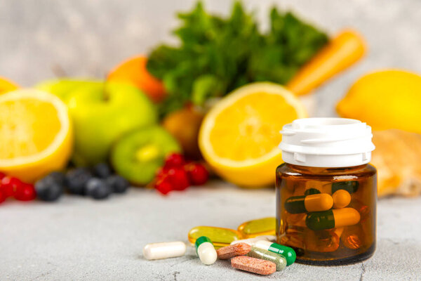 Vitamins and supplements. Variety of vitamin tablets in a jar on a texture background.Multivitamins with fresh and healthy fruits.Food supplements. Flat lay. Space for text.Copy space