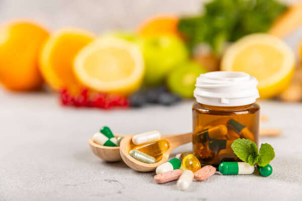 Vitamins and supplements. Variety of vitamin tablets in a jar on a texture background.Multivitamins with fresh and healthy fruits.Food supplements. Flat lay. Space for text.Copy space