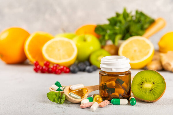 Vitamins and supplements. Variety of vitamin tablets in a jar on a texture background.Multivitamins with fresh and healthy fruits.Food supplements. Flat lay. Space for text.Copy space