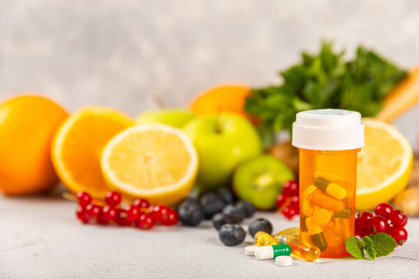 Vitamins and supplements. Variety of vitamin tablets in a jar on a texture background.Multivitamins with fresh and healthy fruits.Food supplements. Flat lay. Space for text.Copy space