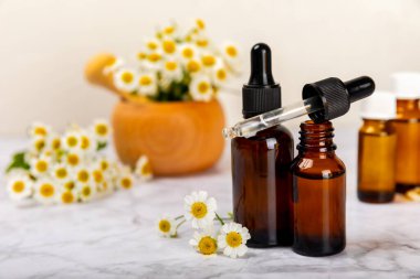 Eski ahşap arka planda papatya yağı bulunan cam şişe. Papatya çiçekleri, yaklaşın. Aromaterapi, spa ve bitkisel ilaç malzemeleri. Güzellik konsepti. Uzayı kopyala. Doğal Kozmetik