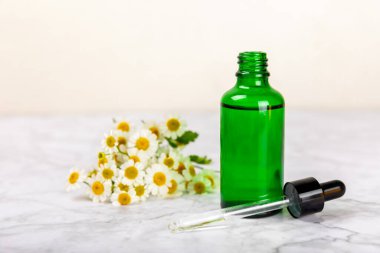 Eski ahşap arka planda papatya yağı bulunan cam şişe. Papatya çiçekleri, yaklaşın. Aromaterapi, spa ve bitkisel ilaç malzemeleri. Güzellik konsepti. Uzayı kopyala. Doğal Kozmetik