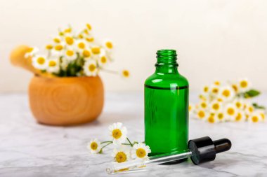 Eski ahşap arka planda papatya yağı bulunan cam şişe. Papatya çiçekleri, yaklaşın. Aromaterapi, spa ve bitkisel ilaç malzemeleri. Güzellik konsepti. Uzayı kopyala. Doğal Kozmetik