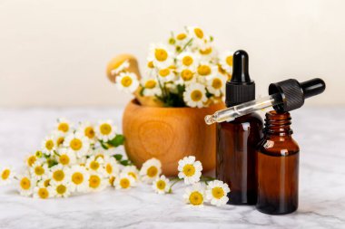 Eski ahşap arka planda papatya yağı bulunan cam şişe. Papatya çiçekleri, yaklaşın. Aromaterapi, spa ve bitkisel ilaç malzemeleri. Güzellik konsepti. Uzayı kopyala. Doğal Kozmetik