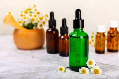 Eski ahşap arka planda papatya yağı bulunan cam şişe. Papatya çiçekleri, yaklaşın. Aromaterapi, spa ve bitkisel ilaç malzemeleri. Güzellik konsepti. Uzayı kopyala. Doğal Kozmetik