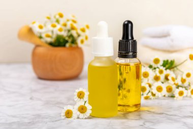 Eski ahşap arka planda papatya yağı bulunan cam şişe. Papatya çiçekleri, yaklaşın. Aromaterapi, spa ve bitkisel ilaç malzemeleri. Güzellik konsepti. Uzayı kopyala. Doğal Kozmetik