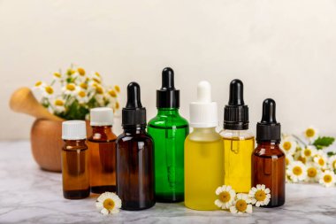 Eski ahşap arka planda papatya yağı bulunan cam şişe. Papatya çiçekleri, yaklaşın. Aromaterapi, spa ve bitkisel ilaç malzemeleri. Güzellik konsepti. Uzayı kopyala. Doğal Kozmetik