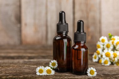 Eski ahşap arka planda papatya yağı bulunan cam şişe. Papatya çiçekleri, yaklaşın. Aromaterapi, spa ve bitkisel ilaç malzemeleri. Güzellik konsepti. Uzayı kopyala. Doğal Kozmetik