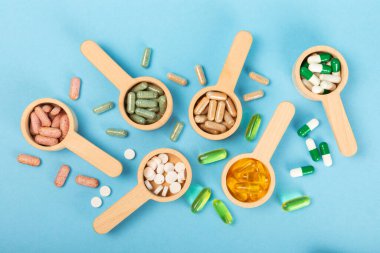 Vitaminler ve takviyeler. Ahşap kaşıklardaki vitamin tabletlerinin dokulu arka planda çeşitliliği. Her gün için multivitamin kompleksi. Besleyici takviyeler. Boşluğu kopyala. Bağışıklık için vitaminler.