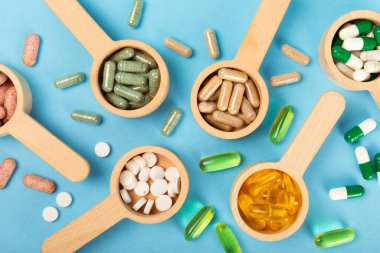 Vitaminler ve takviyeler. Ahşap kaşıklardaki vitamin tabletlerinin dokulu arka planda çeşitliliği. Her gün için multivitamin kompleksi. Besleyici takviyeler. Boşluğu kopyala. Bağışıklık için vitaminler.
