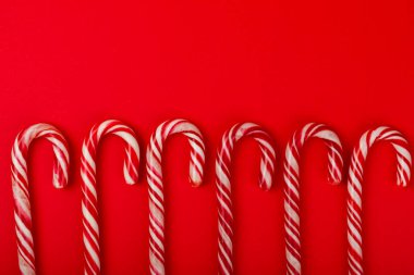 Kırmızı arka planda Noel şekerleri. Tatil tebrik kartı. Noel ve yeni yıl tatili kavramları. Kış. Düz görünüm, üst görünüm, boşluk kopyala.