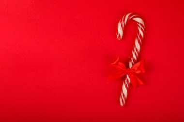 Kırmızı arka planda Noel şekerleri. Tatil tebrik kartı. Noel ve yeni yıl tatili kavramları. Kış. Düz görünüm, üst görünüm, boşluk kopyala.