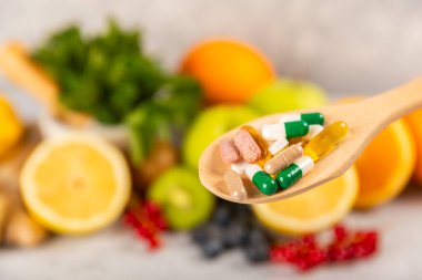 Vitaminler ve takviyeler. Ahşap bir kaşıkta çeşitli vitamin hapları. Taze ve sağlıklı meyveli Multivitaminler. Yiyecek takviyeleri. Düz yatıyordu. Metin için boşluk. Boşluğu kopyala