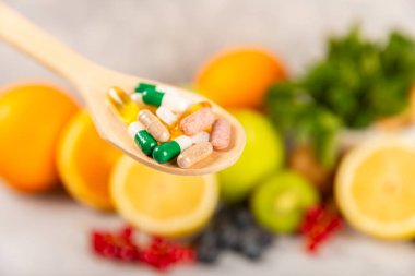 Vitaminler ve takviyeler. Ahşap bir kaşıkta çeşitli vitamin hapları. Taze ve sağlıklı meyveli Multivitaminler. Yiyecek takviyeleri. Düz yatıyordu. Metin için boşluk. Boşluğu kopyala