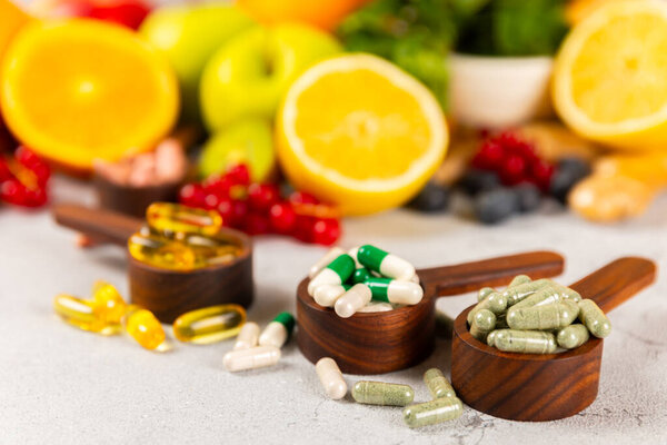 Витамины и добавки. Variety of vitamin tablets in a wooden spoon on a texture background.Multivitamin with fresh and healthy fruits.Food supplements. Плоский лежал. Пространство для текстур