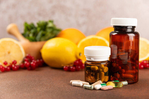 Vitamins and supplements. Variety of vitamin tablets in a jar on a texture background.Multivitamins with fresh and healthy fruits.Food supplements. Flat lay. Space for text.Copy space