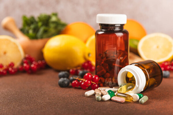 Vitamins and supplements. Variety of vitamin tablets in a jar on a texture background.Multivitamins with fresh and healthy fruits.Food supplements. Flat lay. Space for text.Copy space