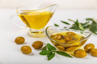 Beyaz dokuya sahip bir şişede zeytin yağı. Zeytin dallı ve meyveli yağ şişesi. Mesaj için yer. kopyalama alanı. Yemek yağı ve salata sosu..