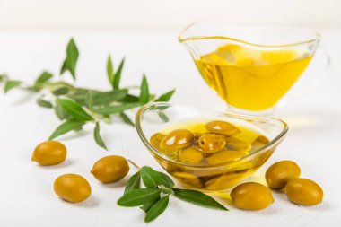 Beyaz dokuya sahip bir şişede zeytin yağı. Zeytin dallı ve meyveli yağ şişesi. Mesaj için yer. kopyalama alanı. Yemek yağı ve salata sosu..