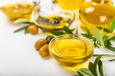 Beyaz dokuya sahip bir şişede zeytin yağı. Zeytin dallı ve meyveli yağ şişesi. Mesaj için yer. kopyalama alanı. Yemek yağı ve salata sosu..