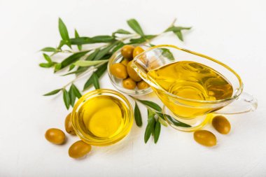 Beyaz dokuya sahip bir şişede zeytin yağı. Zeytin dallı ve meyveli yağ şişesi. Mesaj için yer. kopyalama alanı. Yemek yağı ve salata sosu..