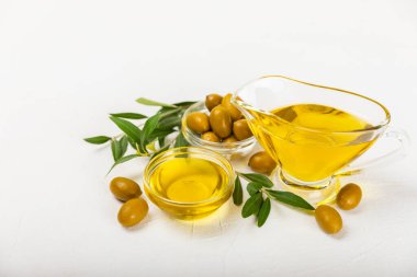 Beyaz dokuya sahip bir şişede zeytin yağı. Zeytin dallı ve meyveli yağ şişesi. Mesaj için yer. kopyalama alanı. Yemek yağı ve salata sosu..