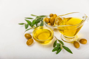 Beyaz dokuya sahip bir şişede zeytin yağı. Zeytin dallı ve meyveli yağ şişesi. Mesaj için yer. kopyalama alanı. Yemek yağı ve salata sosu..