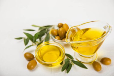 Beyaz dokuya sahip bir şişede zeytin yağı. Zeytin dallı ve meyveli yağ şişesi. Mesaj için yer. kopyalama alanı. Yemek yağı ve salata sosu..