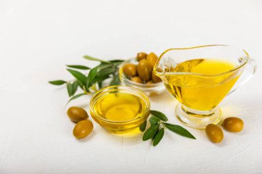 Beyaz dokuya sahip bir şişede zeytin yağı. Zeytin dallı ve meyveli yağ şişesi. Mesaj için yer. kopyalama alanı. Yemek yağı ve salata sosu..