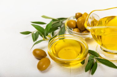 Beyaz dokuya sahip bir şişede zeytin yağı. Zeytin dallı ve meyveli yağ şişesi. Mesaj için yer. kopyalama alanı. Yemek yağı ve salata sosu..