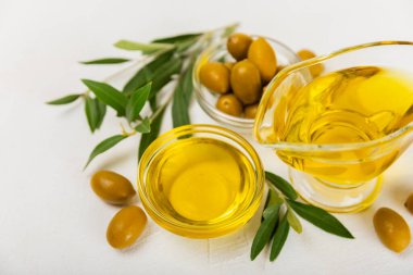 Beyaz dokuya sahip bir şişede zeytin yağı. Zeytin dallı ve meyveli yağ şişesi. Mesaj için yer. kopyalama alanı. Yemek yağı ve salata sosu..
