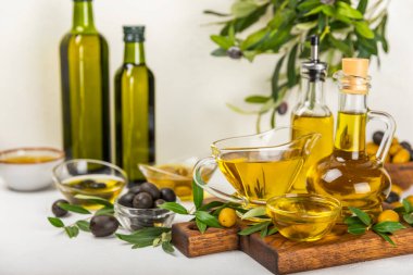 Beyaz dokuya sahip bir şişede zeytin yağı. Zeytin dallı ve meyveli yağ şişesi. Mesaj için yer. kopyalama alanı. Yemek yağı ve salata sosu..