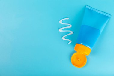 Mavi arka planda güneş kremi. SPF kremi. Güneş koruması. Ultraviyole koruma. Yaz. Dinlenme ve tatil kavramı. Yaz havası. Tasarım. - Model. Tatil. Güzellik.