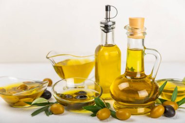 Beyaz dokuya sahip bir şişede zeytin yağı. Zeytin dallı ve meyveli yağ şişesi. Mesaj için yer. kopyalama alanı. Yemek yağı ve salata sosu..
