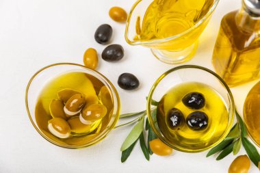 Beyaz dokuya sahip bir şişede zeytin yağı. Zeytin dallı ve meyveli yağ şişesi. Mesaj için yer. kopyalama alanı. Yemek yağı ve salata sosu..