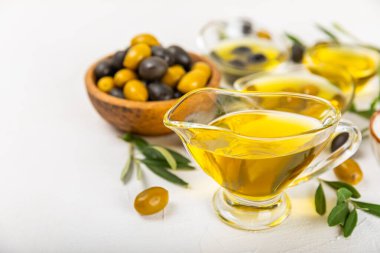 Beyaz dokuya sahip bir şişede zeytin yağı. Zeytin dallı ve meyveli yağ şişesi. Mesaj için yer. kopyalama alanı. Yemek yağı ve salata sosu..