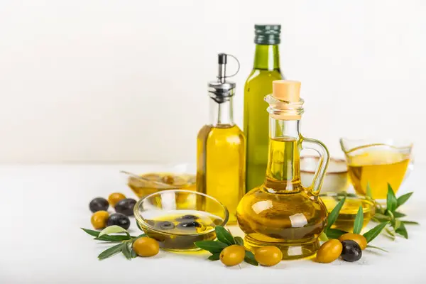 Olive oil in a bottle on a white texture background. Oil bottle with branches and fruits of olives. Place for text. copy space. cooking oil and salad dressing.