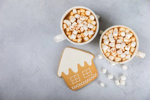 Hot drink with marshmallows and candy cane in a white cup on a texture table.Cozy seasonal holidays.Hot cocoa with gingerbread Christmas cookies.Hot chocolate with marshmallow and spices.Copy space.