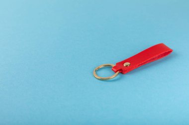 Mavi arka planda anahtarlığı olan deri bir anahtarlık. Gayrimenkul ve eve taşınma ya da mülk kiralama kavramları. Mülk almak. Model anahtarlık. Boşluğu kopyala.