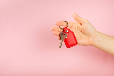 Pembe arka planda anahtarlığı olan deri bir anahtarlık. Gayrimenkul ve eve taşınma ya da mülk kiralama kavramları. Mülk almak. Model anahtarlık. Boşluğu kopyala.